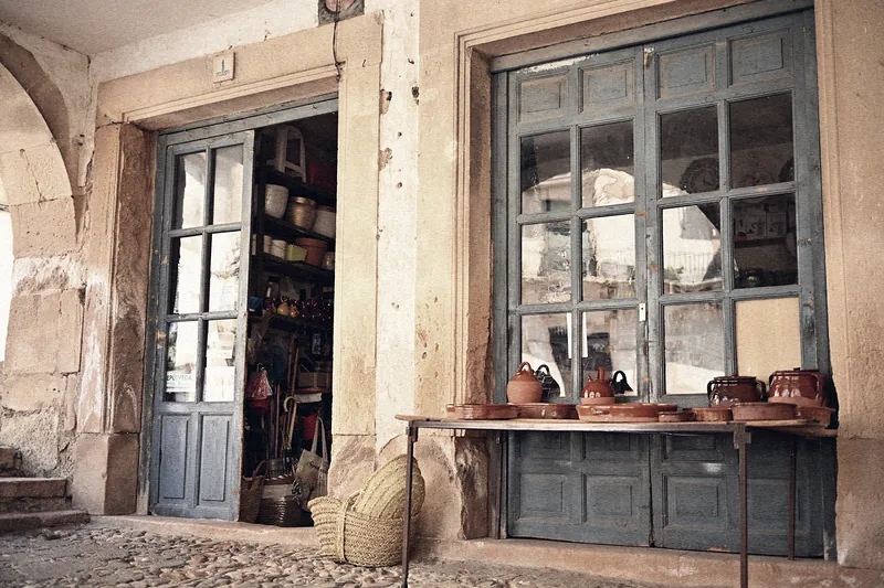 Puerta de un comercio rústico de Sepúlveda, con una mesa en la calle donde se exponen piezas de cerámica tradicional.