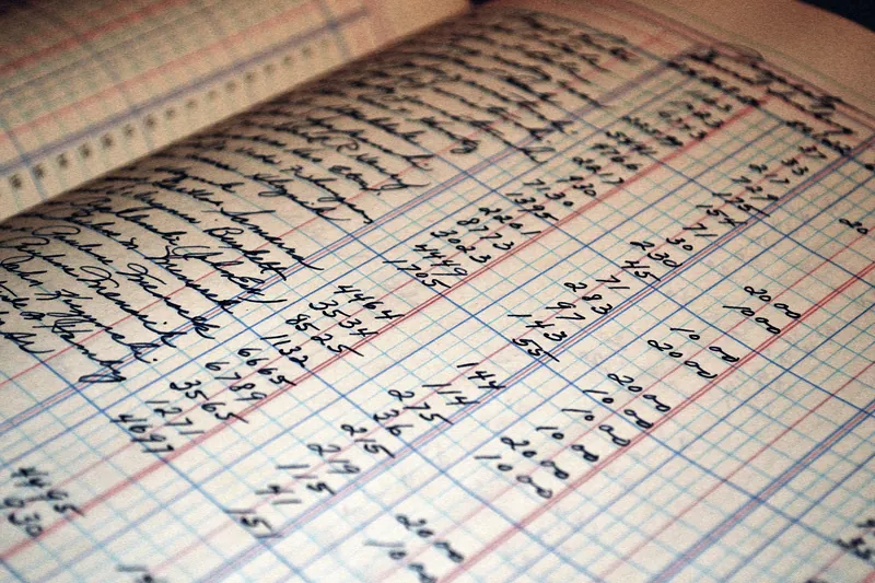 Libro de contabilidad antiguo con columnas de cifras escritas a mano sobre papel rayado.
